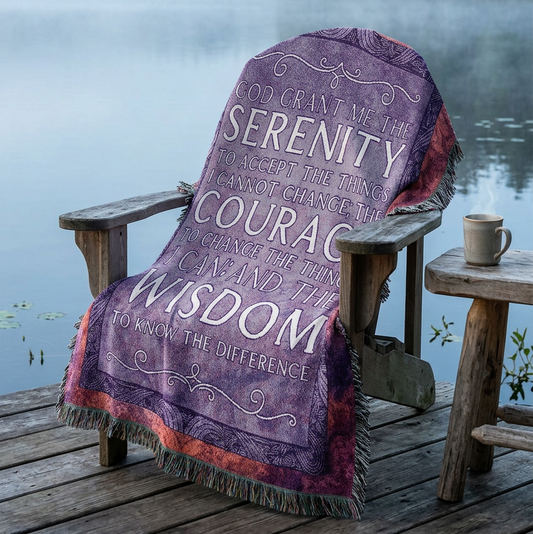 A square woven throw blanket with fringe edges, featuring a purple and lavender background with a central white typographic quote about serenity, courage, wisdom, and acceptance. The outer border has a mottled pattern of pink, orange, and purple tones.