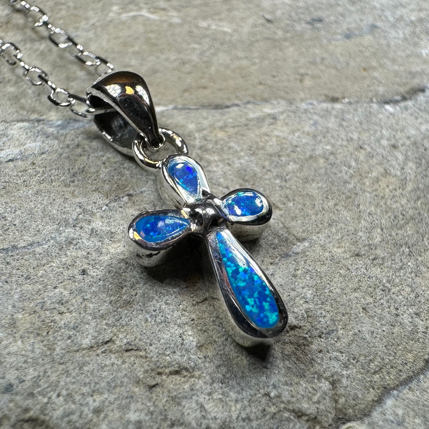 Opal cross necklace on a stone surface