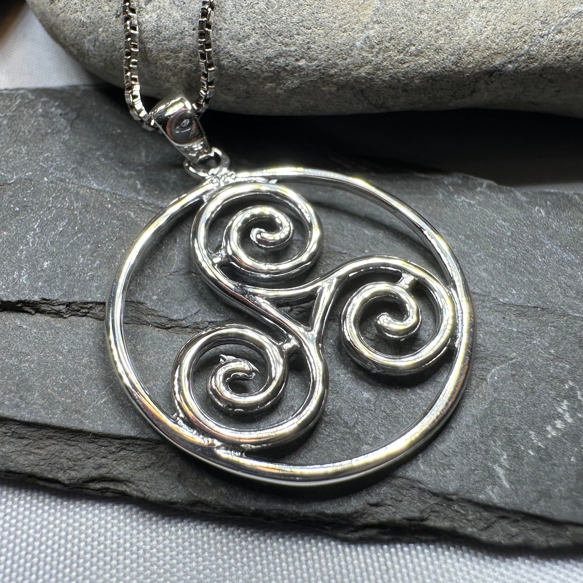 Silver Triskele pendant necklace on a stone background