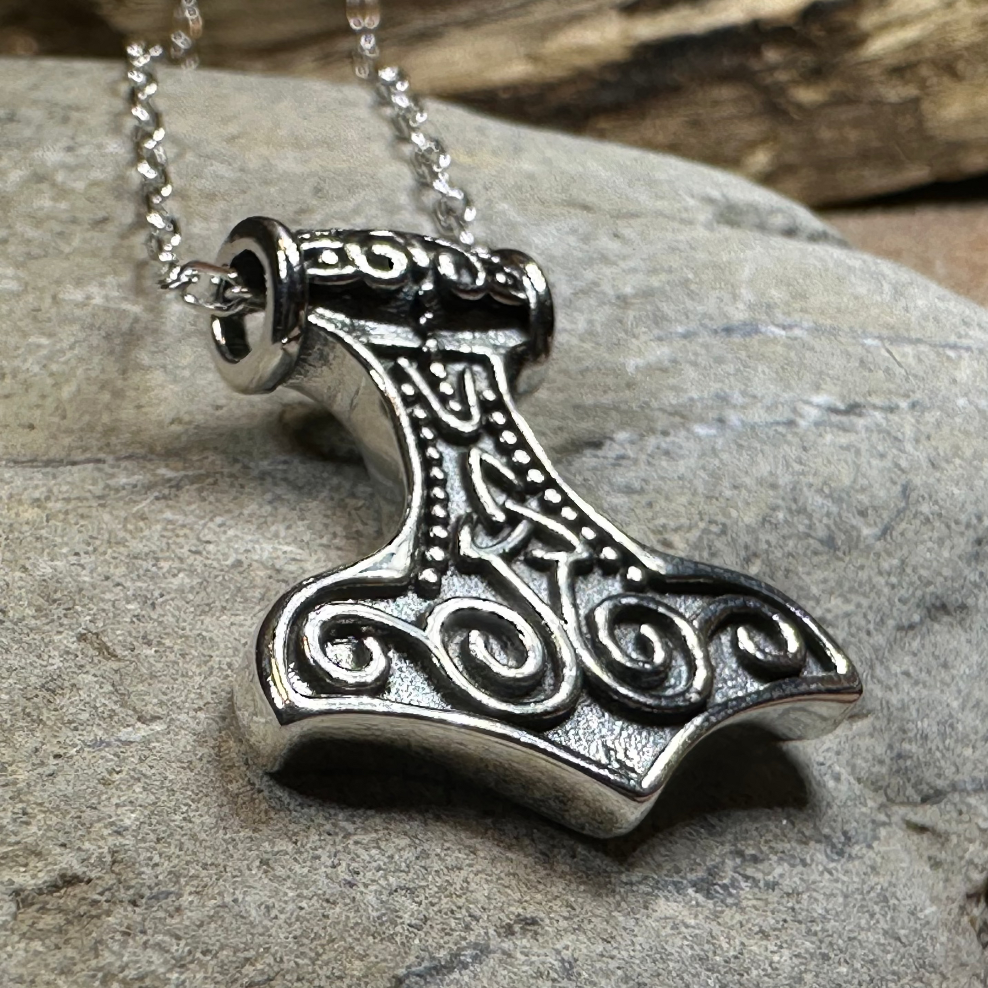 Silver Mjällnir pendant on a chain against a stone background