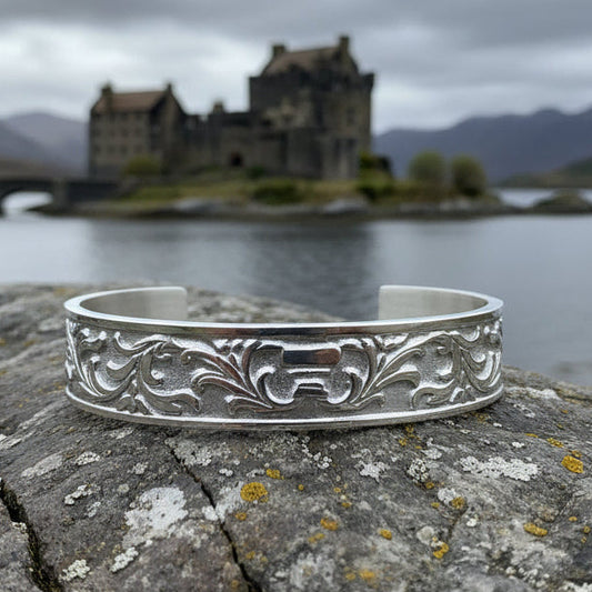 Silver bracelet with intricate designs on a green leafy background